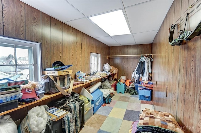 miscellaneous room with light floors, a wealth of natural light, a drop ceiling, and wood walls