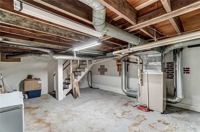 unfinished below grade area featuring heating unit, stairway, and white refrigerator