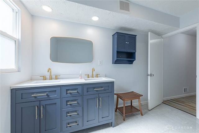 bathroom featuring visible vents, a sink, and a textured ceiling