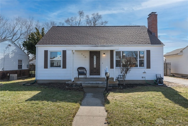 bungalow-style home with a chimney, roof with shingles, covered porch, cooling unit, and a front lawn