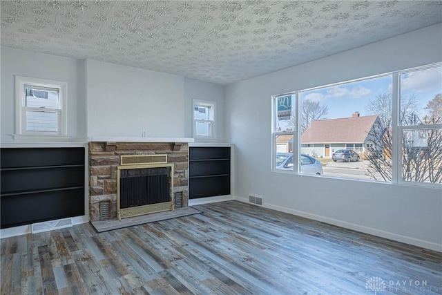 unfurnished living room with a textured ceiling, wood finished floors, and baseboards