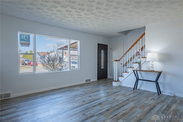 entryway with stairs, wood finished floors, visible vents, and baseboards