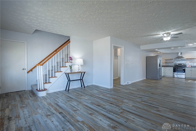 unfurnished living room with a textured ceiling, stairway, dark wood finished floors, and baseboards