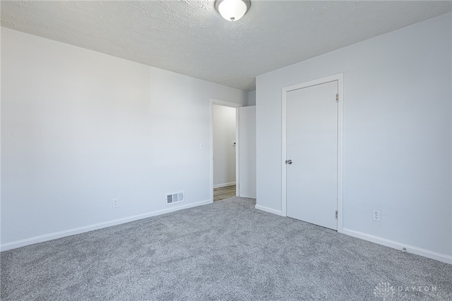 unfurnished bedroom featuring carpet floors, baseboards, visible vents, and a textured ceiling