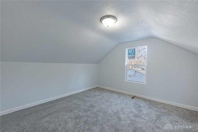 bonus room with carpet floors, lofted ceiling, a textured ceiling, and baseboards