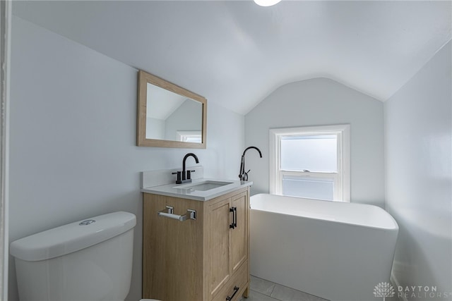 bathroom with lofted ceiling, a freestanding tub, toilet, and vanity