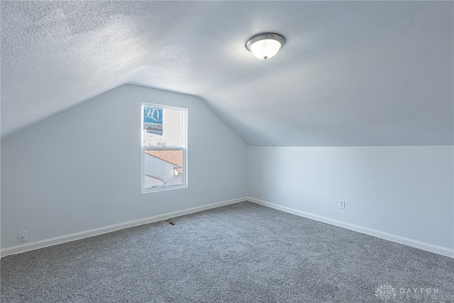 additional living space with carpet floors, lofted ceiling, a textured ceiling, and baseboards