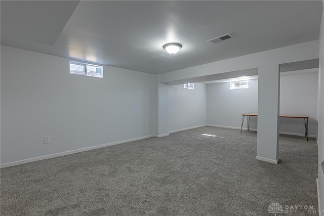 basement featuring carpet floors, visible vents, and baseboards