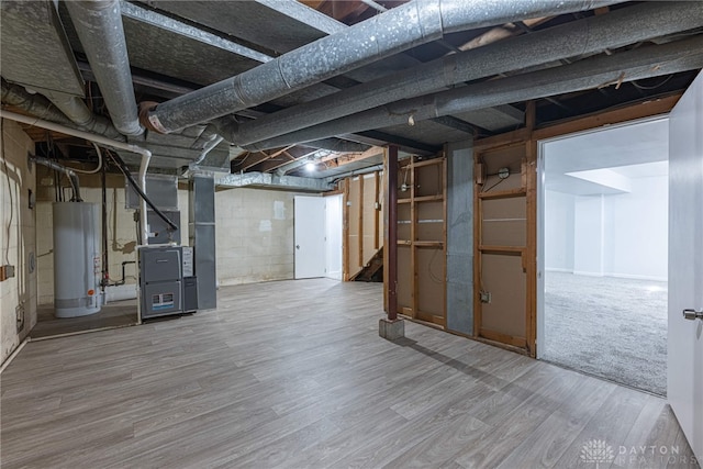 unfinished basement with water heater, wood finished floors, stairs, and heating unit