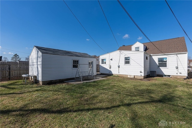 rear view of property with a lawn, roof with shingles, an outbuilding, fence, and cooling unit