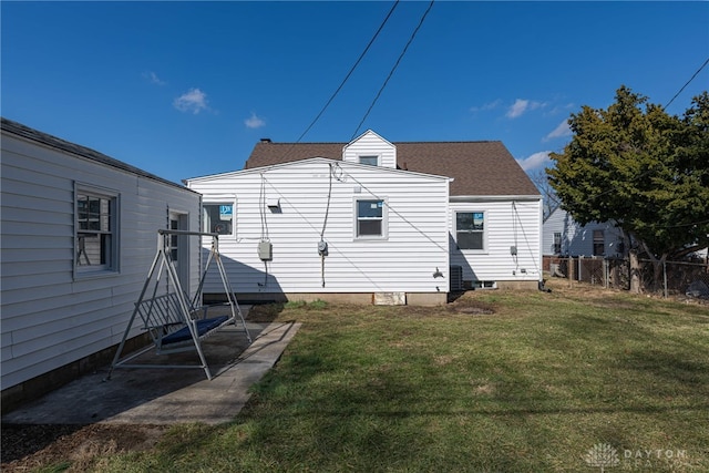 back of house with fence, a lawn, and roof with shingles