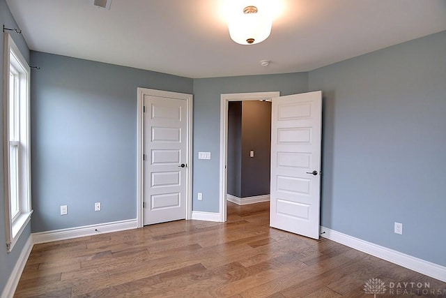 9471 Banyan Ct, Dayton, OH 45458 - unfurnished bedroom featuring multiple windows, baseboards, and wood finished floors