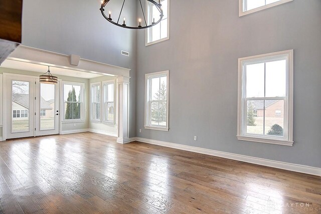 9471 Banyan Ct, Dayton, OH 45458 - unfurnished living room featuring a chandelier, hardwood / wood-style flooring, visible vents, baseboards, and a wealth of natural light