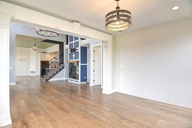 9471 Banyan Ct, Dayton, OH 45458 - unfurnished room featuring a notable chandelier, brick wall, a fireplace, wood finished floors, and visible vents