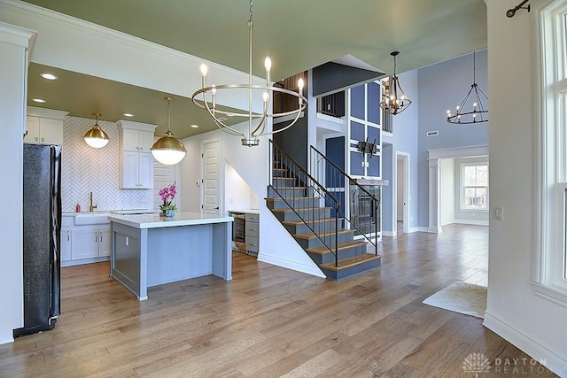 9471 Banyan Ct, Dayton, OH 45458 - kitchen featuring a notable chandelier, white cabinets, light wood-type flooring, freestanding refrigerator, and a center island