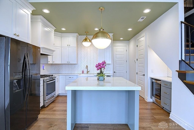 9471 Banyan Ct, Dayton, OH 45458 - kitchen with wine cooler, visible vents, stainless steel range with gas stovetop, wood finished floors, and black fridge