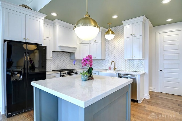 9471 Banyan Ct, Dayton, OH 45458 - kitchen featuring white cabinets, appliances with stainless steel finishes, decorative light fixtures, light wood-style floors, and a sink