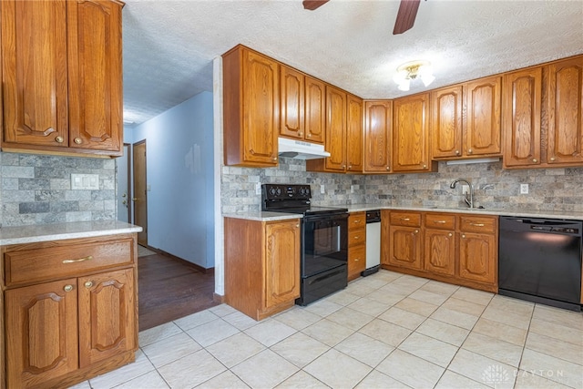 kitchen featuring black appliances, under cabinet range hood, brown cabinetry, and light countertops