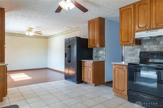 kitchen with brown cabinets, black appliances, under cabinet range hood, and light countertops