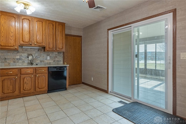 kitchen featuring black dishwasher, visible vents, brown cabinets, light countertops, and a sink