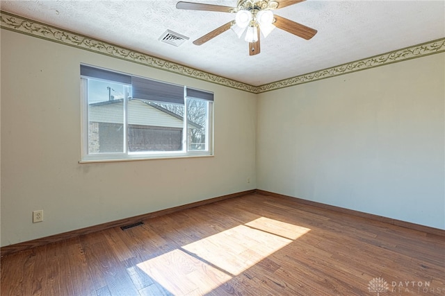 unfurnished room featuring baseboards, a textured ceiling, visible vents, and wood finished floors