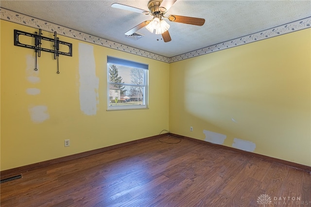 unfurnished room featuring a textured ceiling, wood finished floors, visible vents, and baseboards