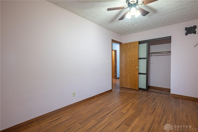 unfurnished bedroom with a closet, a ceiling fan, a textured ceiling, wood finished floors, and baseboards