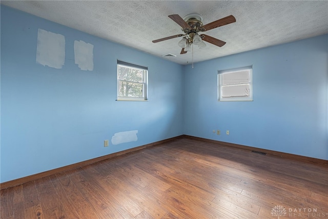 unfurnished room with a textured ceiling, hardwood / wood-style floors, and visible vents