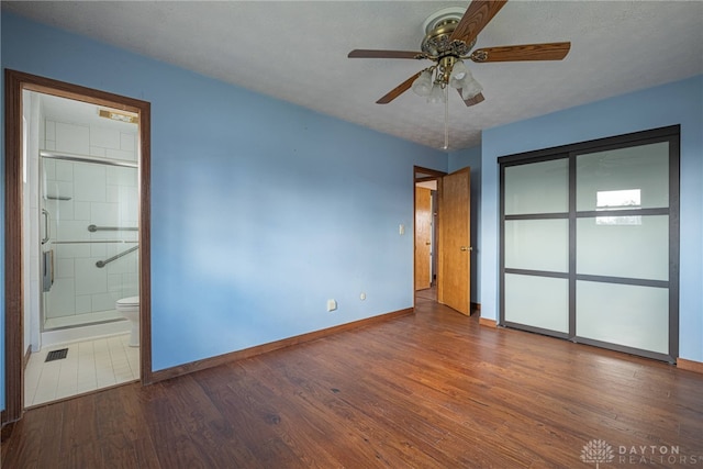 unfurnished bedroom with a textured ceiling, wood finished floors, visible vents, baseboards, and a closet