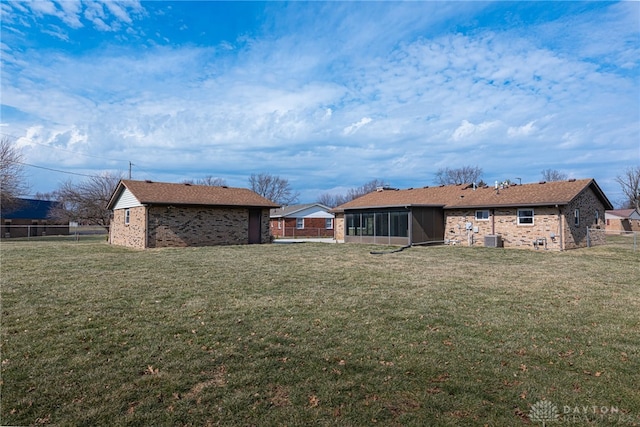 view of yard with a sunroom, fence, an outdoor structure, and central AC unit