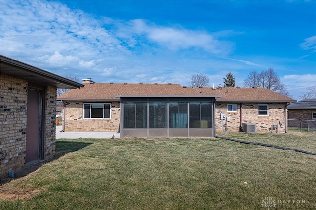 back of property with brick siding, a lawn, fence, and a sunroom