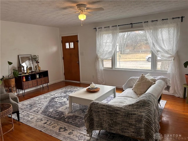 living area featuring wood-type flooring, baseboards, and a textured ceiling