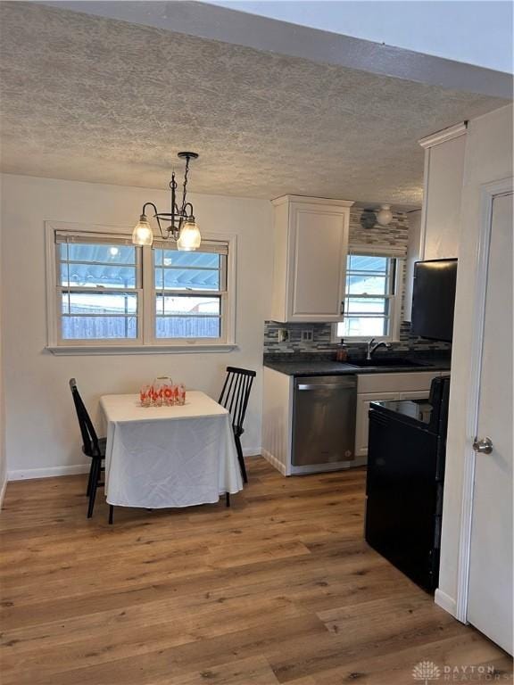 dining area with a textured ceiling, baseboards, and wood finished floors