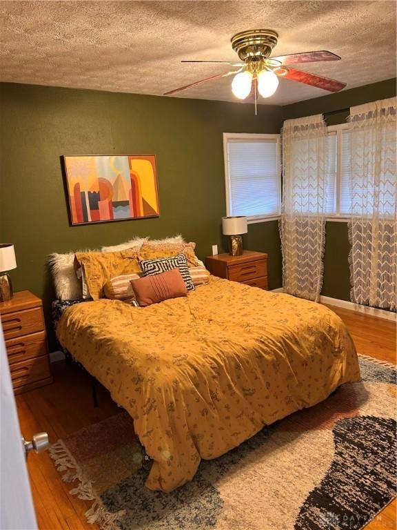 bedroom featuring a ceiling fan, a textured ceiling, and wood finished floors