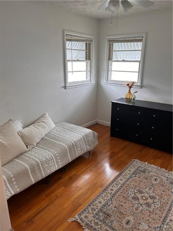 bedroom with hardwood / wood-style flooring, ceiling fan, and baseboards