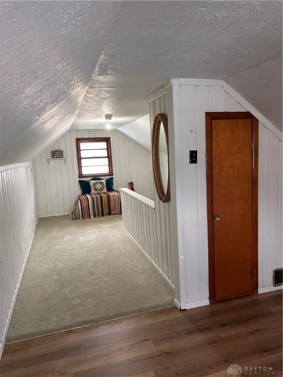 additional living space featuring a textured ceiling, wood finished floors, and lofted ceiling