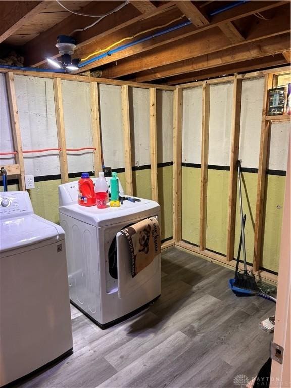 clothes washing area featuring laundry area, washer and clothes dryer, and wood finished floors