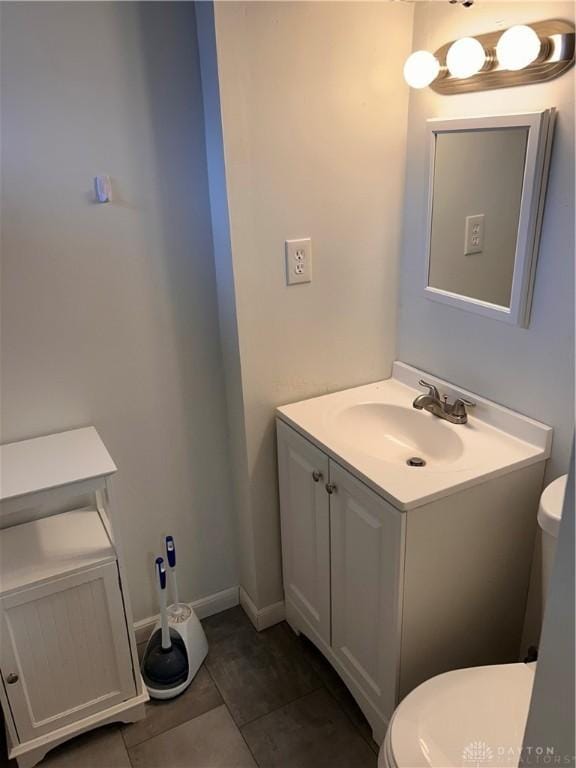 bathroom featuring baseboards, vanity, toilet, and tile patterned floors