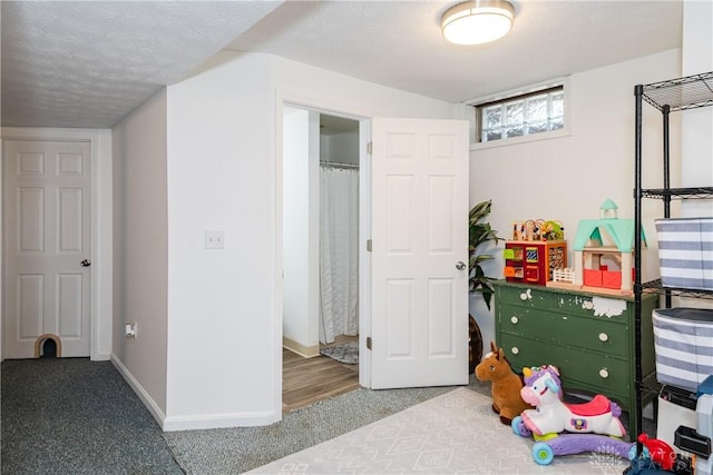 carpeted bedroom featuring a textured ceiling and baseboards