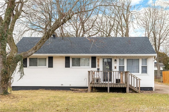 view of front of home with roof with shingles, fence, and a front lawn