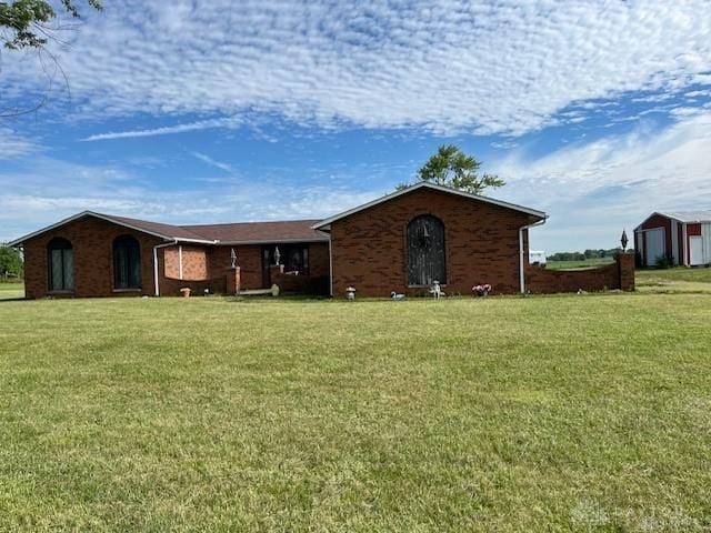 view of front of house featuring an outbuilding, brick siding, and a front yard