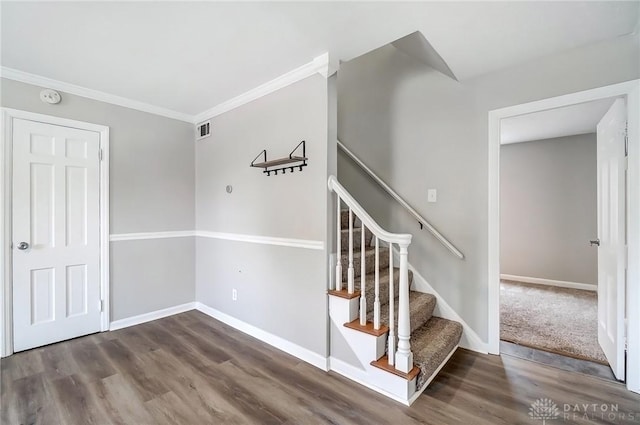 staircase featuring visible vents, baseboards, wood finished floors, and ornamental molding