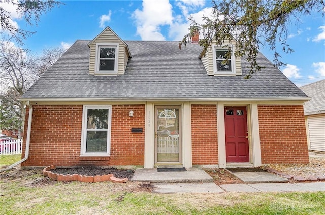 view of front of property with roof with shingles, fence, and brick siding