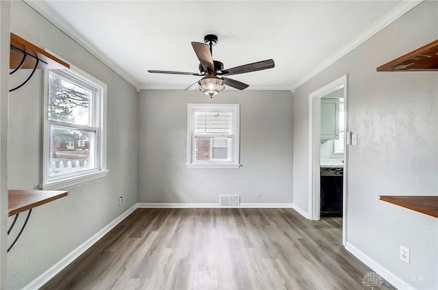 unfurnished room with crown molding, visible vents, plenty of natural light, and baseboards