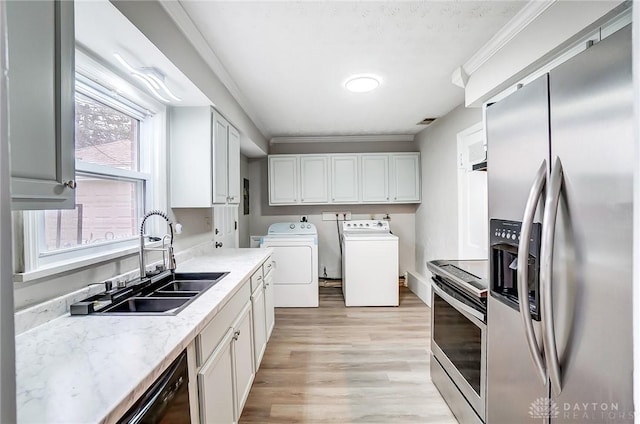 kitchen with crown molding, washer and clothes dryer, appliances with stainless steel finishes, white cabinets, and a sink