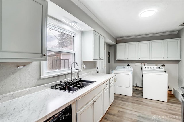 laundry room with washing machine and dryer, laundry area, a sink, ornamental molding, and light wood-type flooring