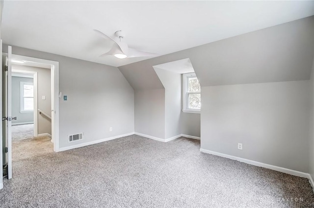 additional living space featuring carpet flooring, visible vents, vaulted ceiling, and baseboards