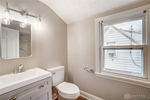 bathroom featuring toilet, plenty of natural light, baseboards, and vanity