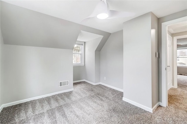 additional living space featuring vaulted ceiling, carpet floors, visible vents, and baseboards