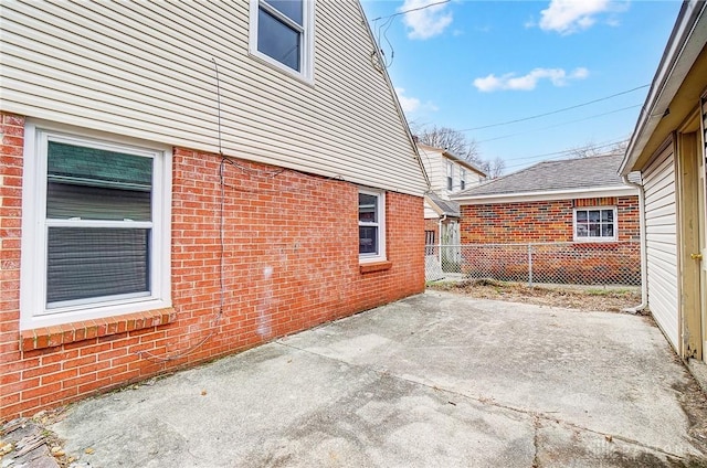 exterior space with a patio area, fence, and brick siding